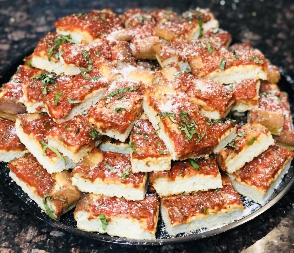 Party-cut tomato pie tray at Ambler Pizza topped with sauce, grated cheese and fresh basil